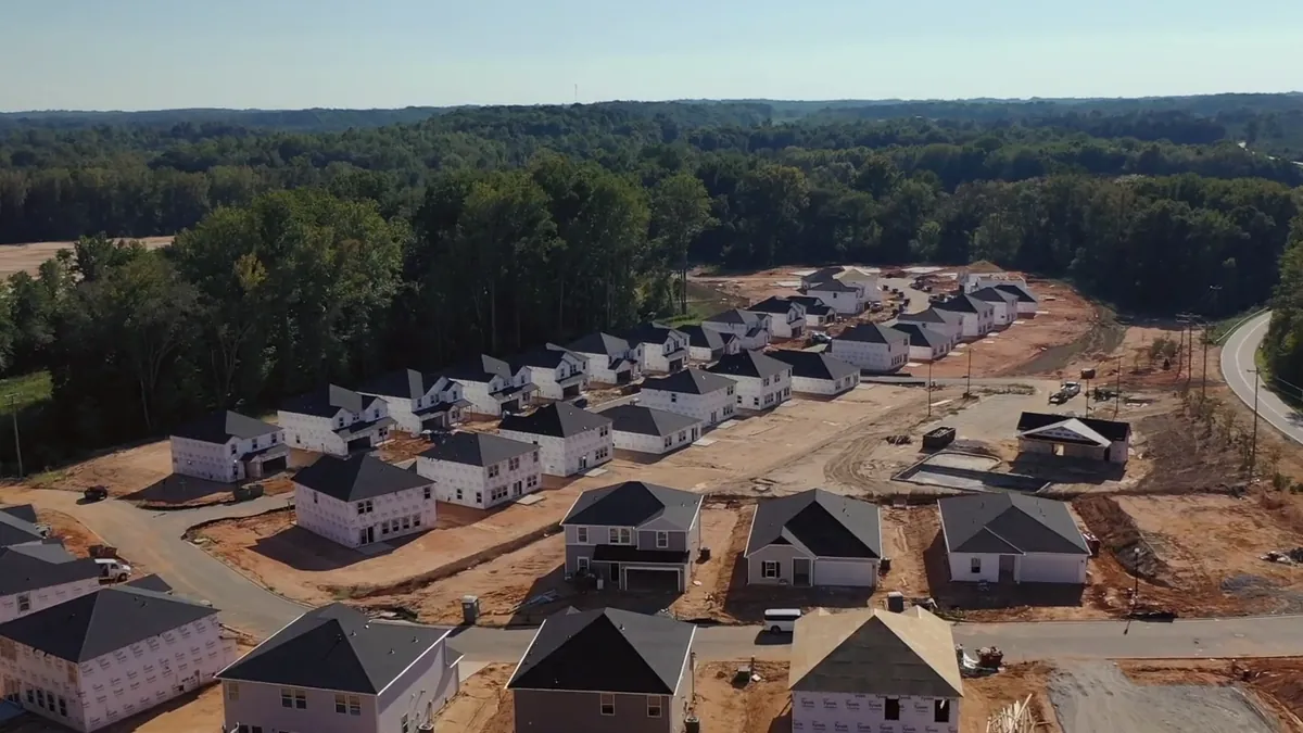 Aerial view of a community under construction, lots cleared and framed