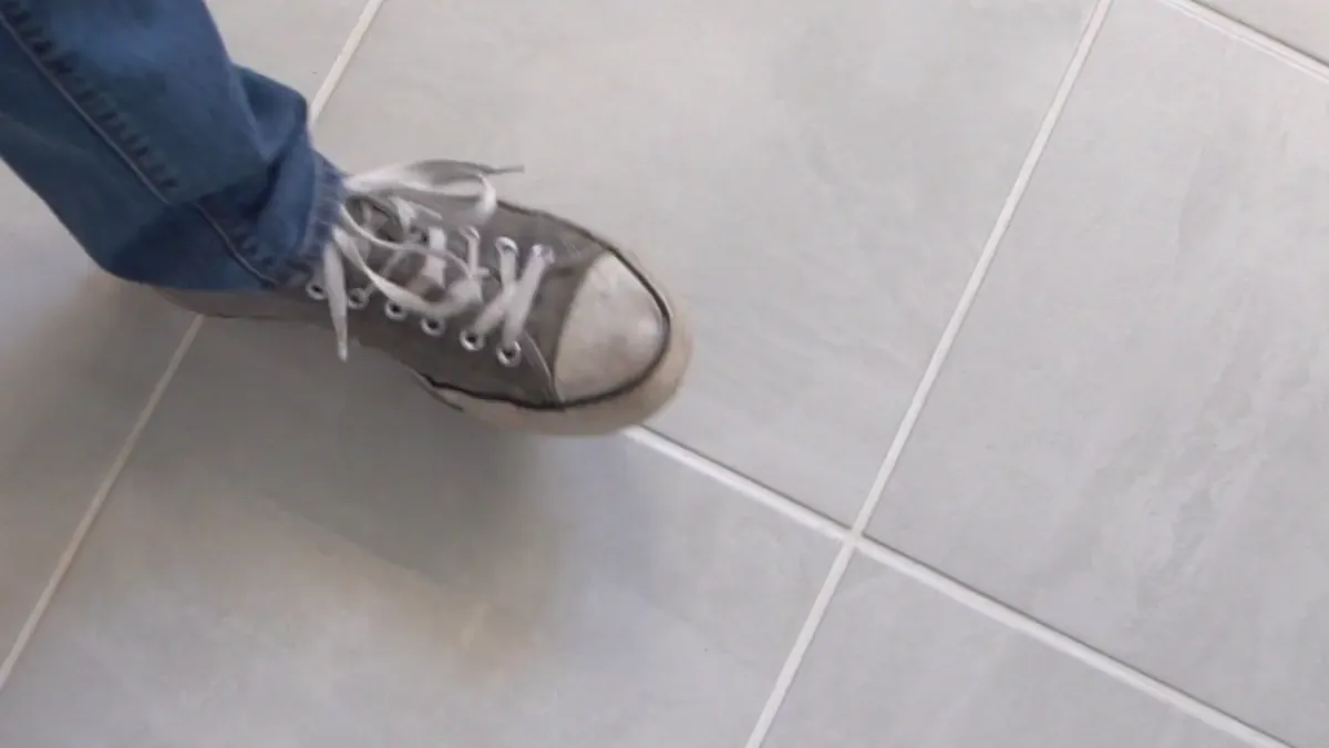 A sneaker crossing a finished tile floor